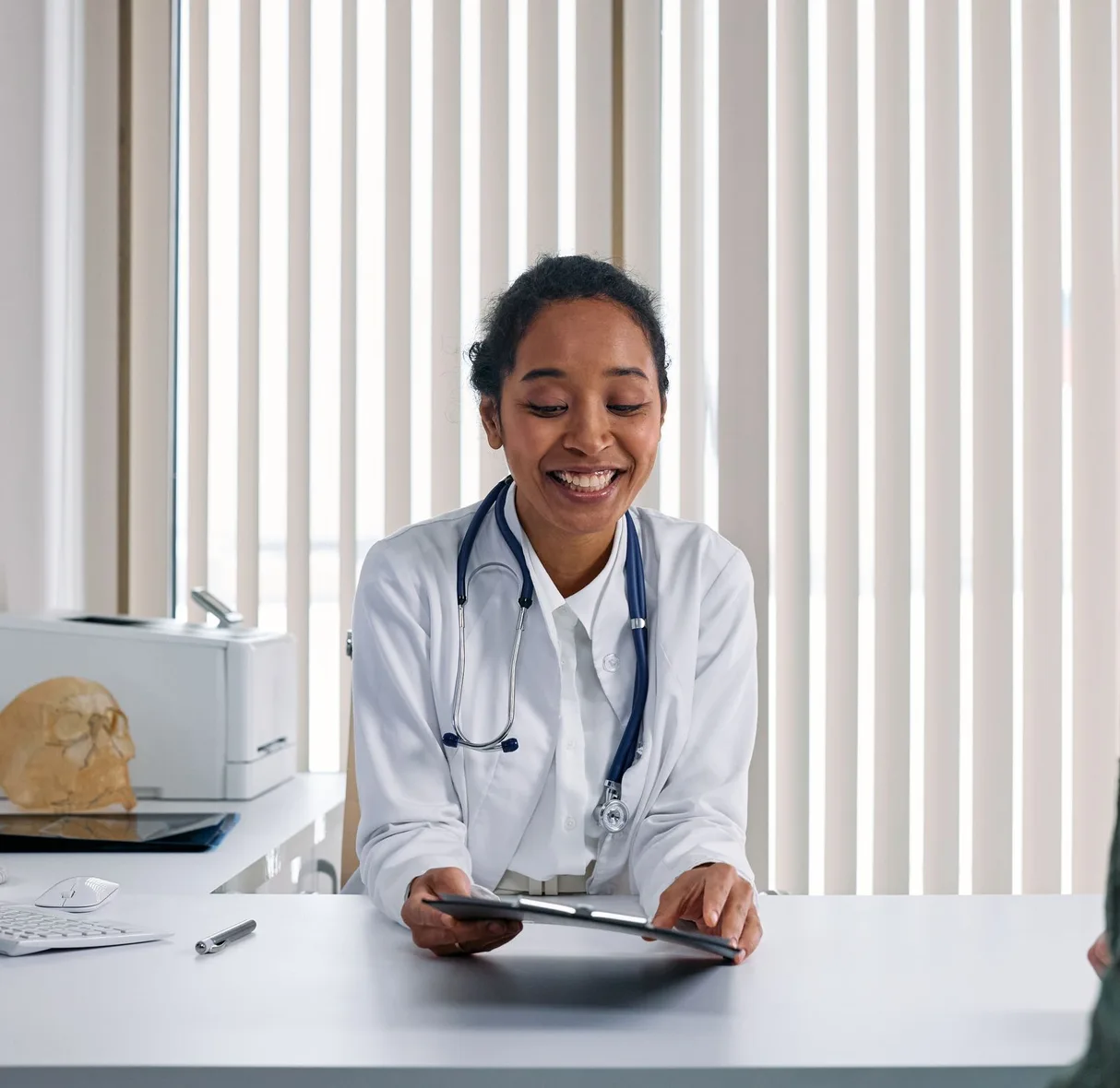 A clinician talking with a patient across a desk.