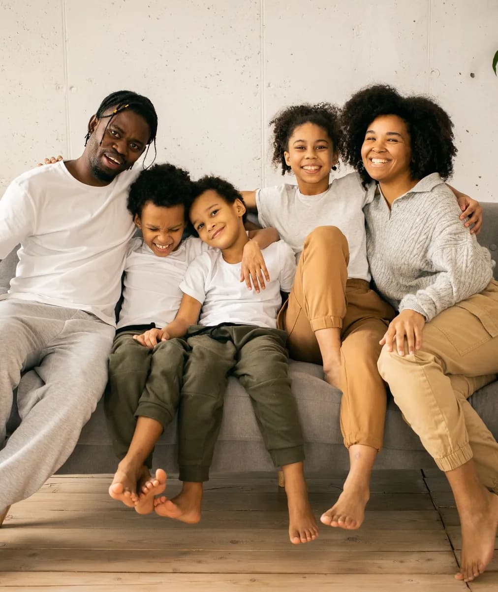 Parents and two children sitting together on a sofa at home.